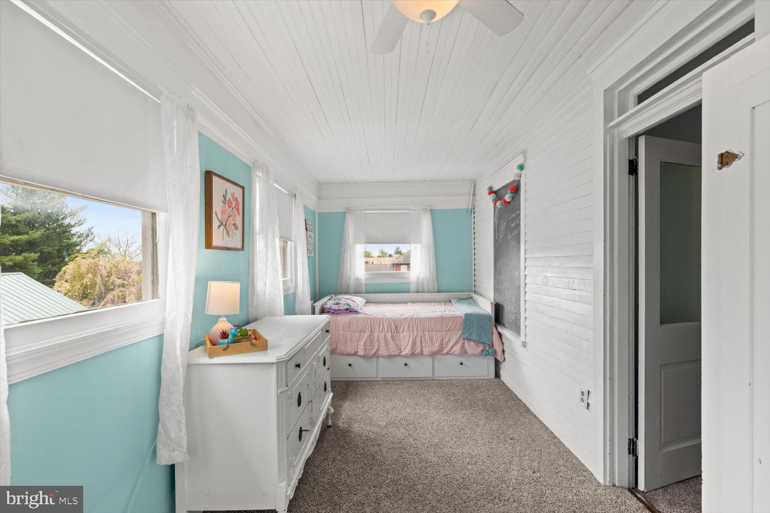 Bedroom with turquoise walls, white beadboard, and a built-in daybed beneath the window.