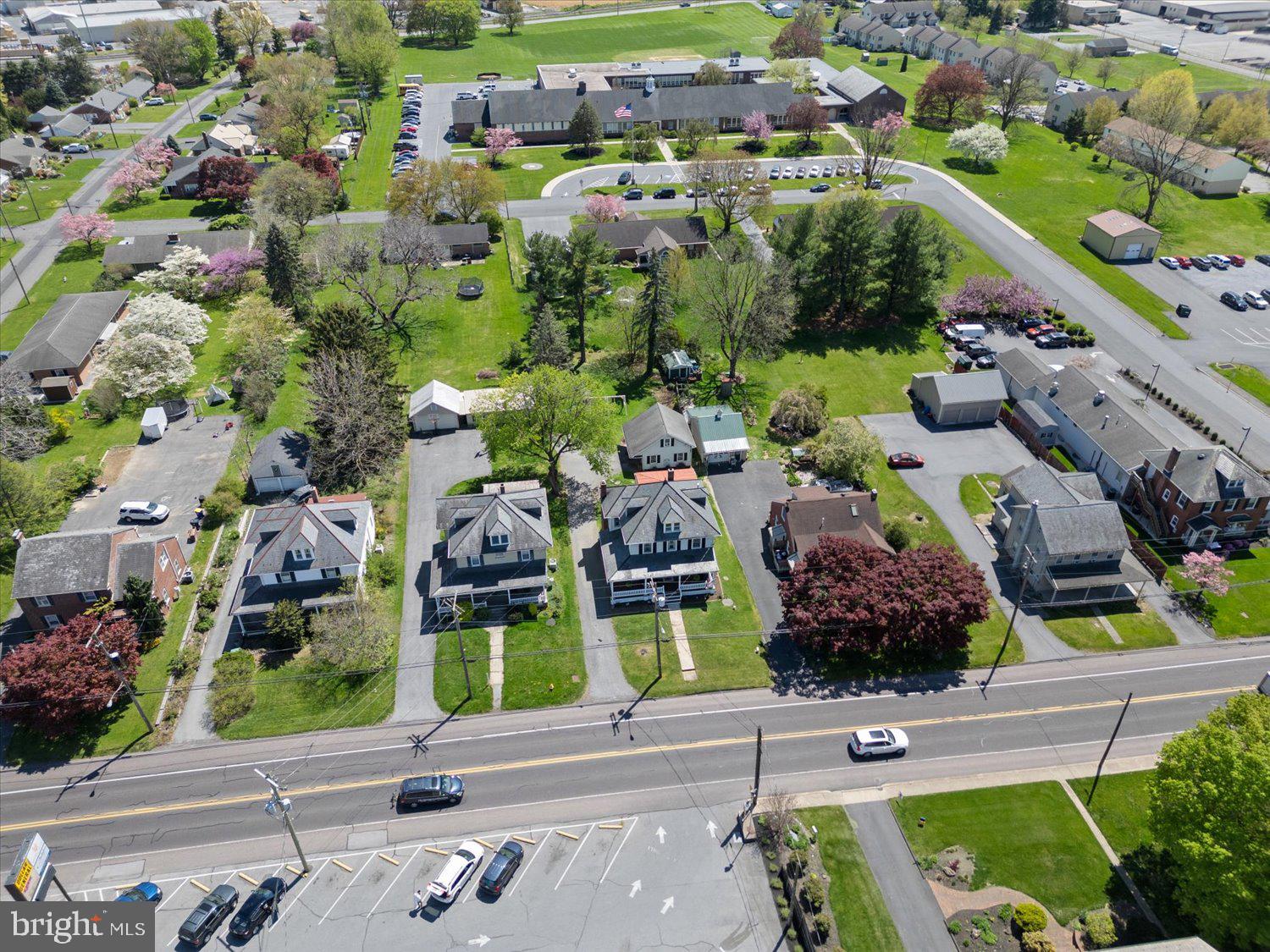 Aerial view of the property and surrounding homes, parking areas, and landscaped grounds.