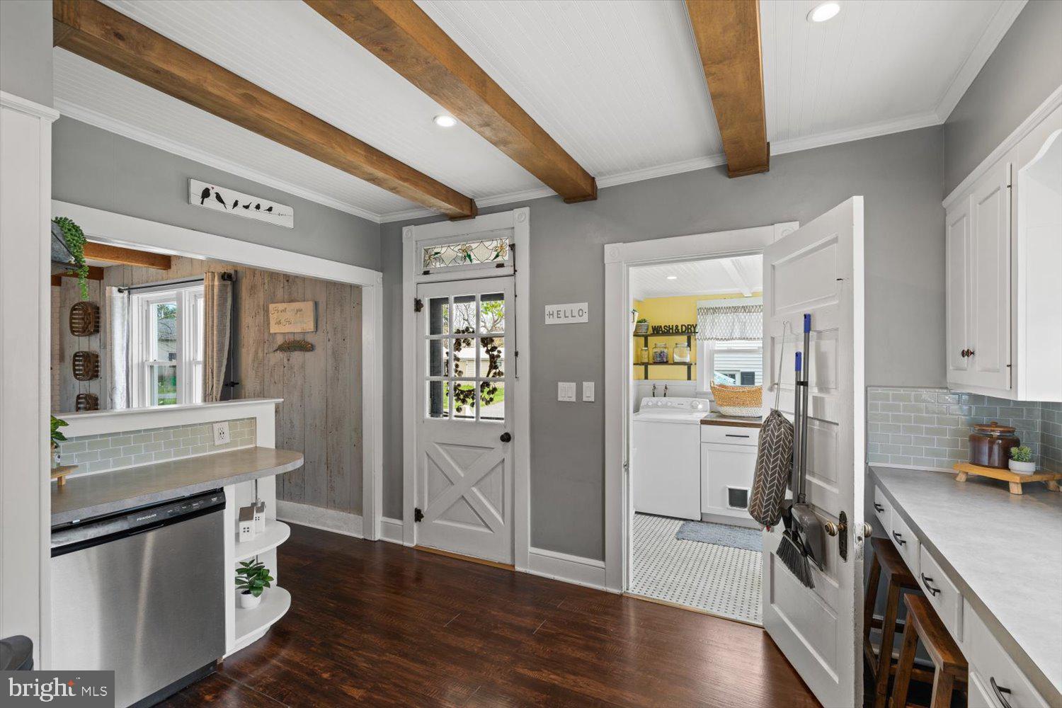 Kitchen with exposed wood ceiling beams and a doorway into the laundry room.