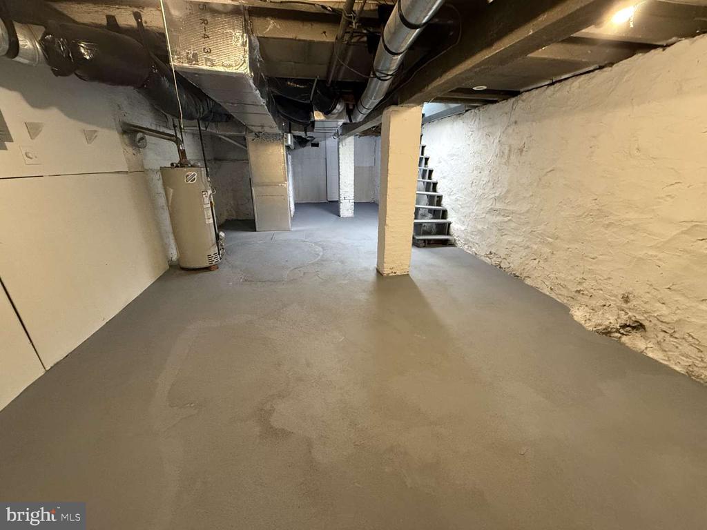 Unfinished basement with exposed ductwork, a water heater, and stairs.