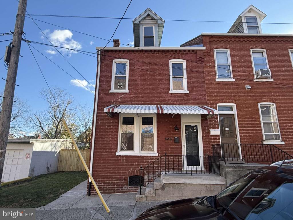 Red-brick rowhouse with a striped awning and concrete front steps.