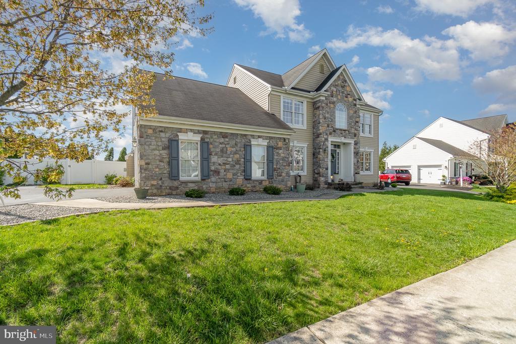 Two-story home with a stone facade, light siding, and a broad front lawn.
