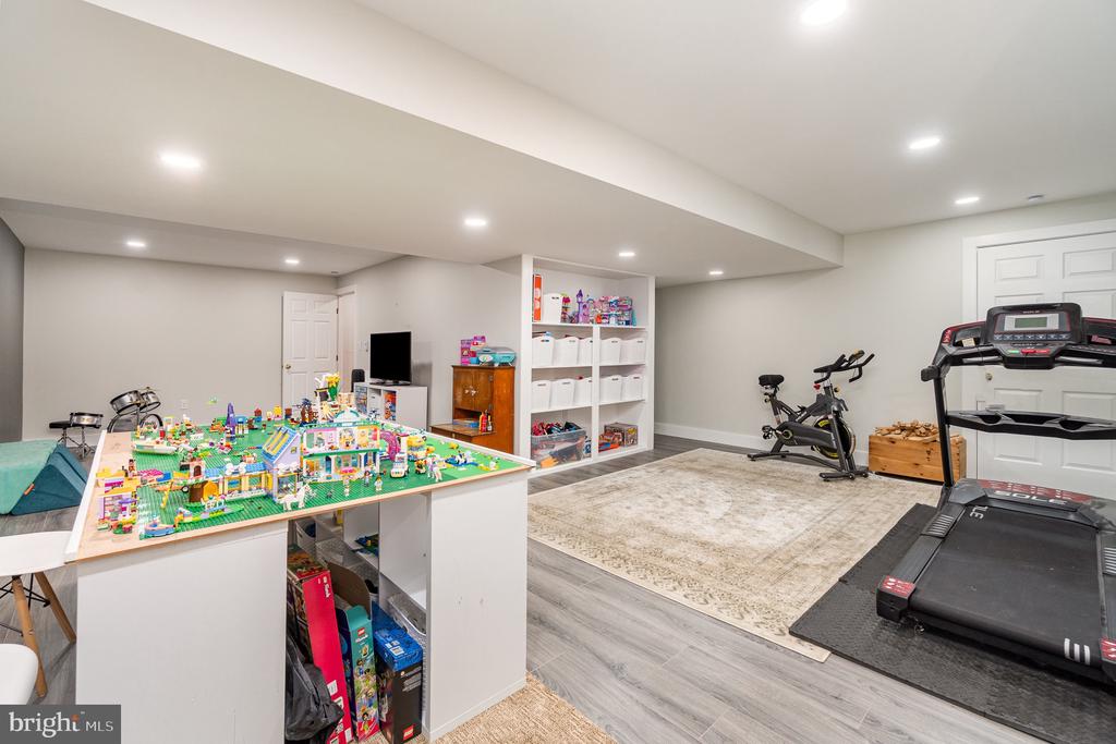 Recreation room with a colorful toy table, built-in storage shelves, stationary bike, and treadmill.