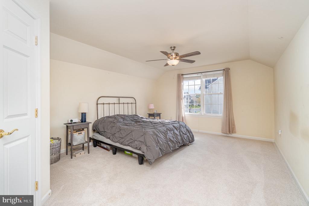 Bedroom with gray bedding, metal bed frame, and a curtained window.