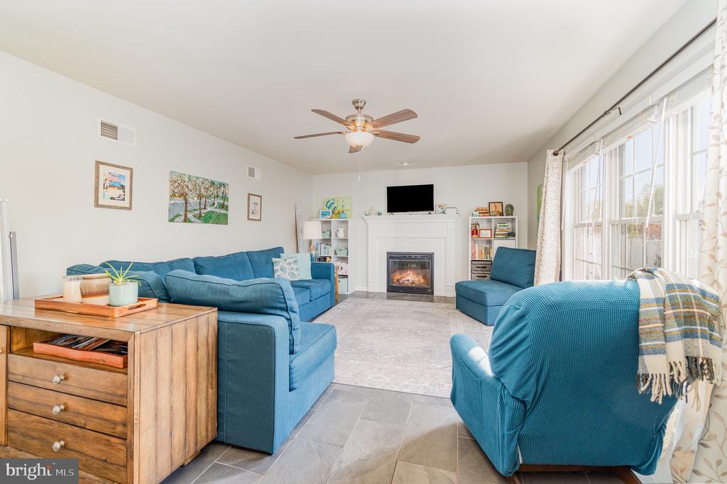 Living room with blue seating, a lit fireplace, and large curtained windows.