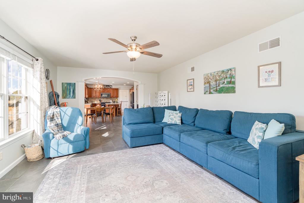 Living room with a blue sectional sofa, matching armchair, and arched opening to the kitchen.