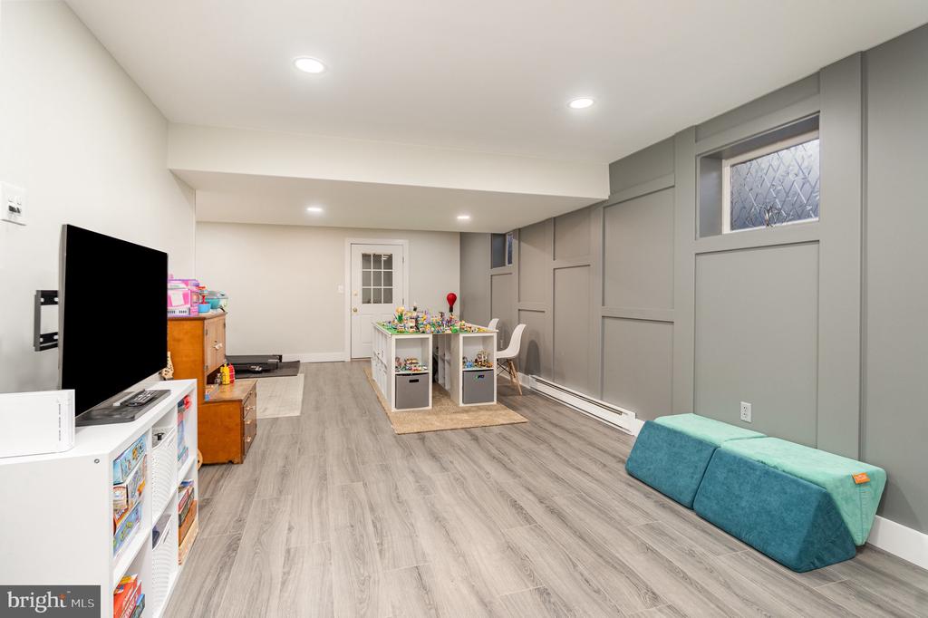 Finished basement recreation room with a children's activity table, toy storage, and teal floor cushions.