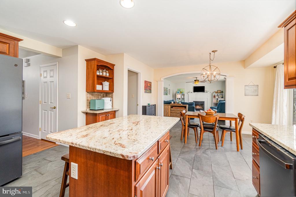 Kitchen with a large granite island, wood cabinetry, and an adjoining dining area.