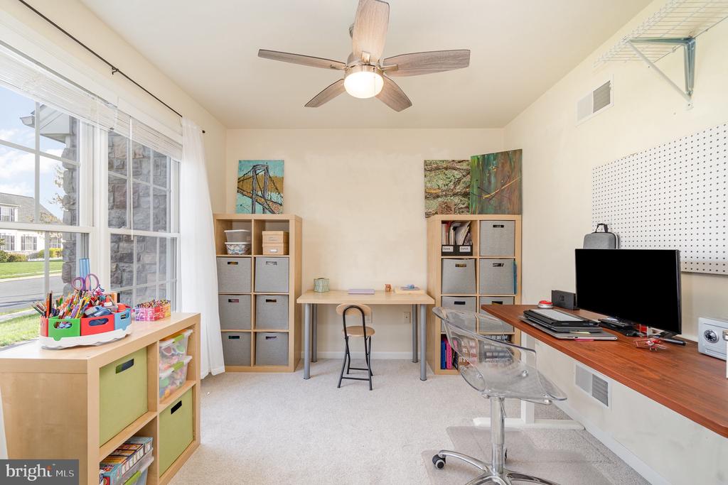 Home office with large windows, storage cubbies, a craft table, and a computer workstation.