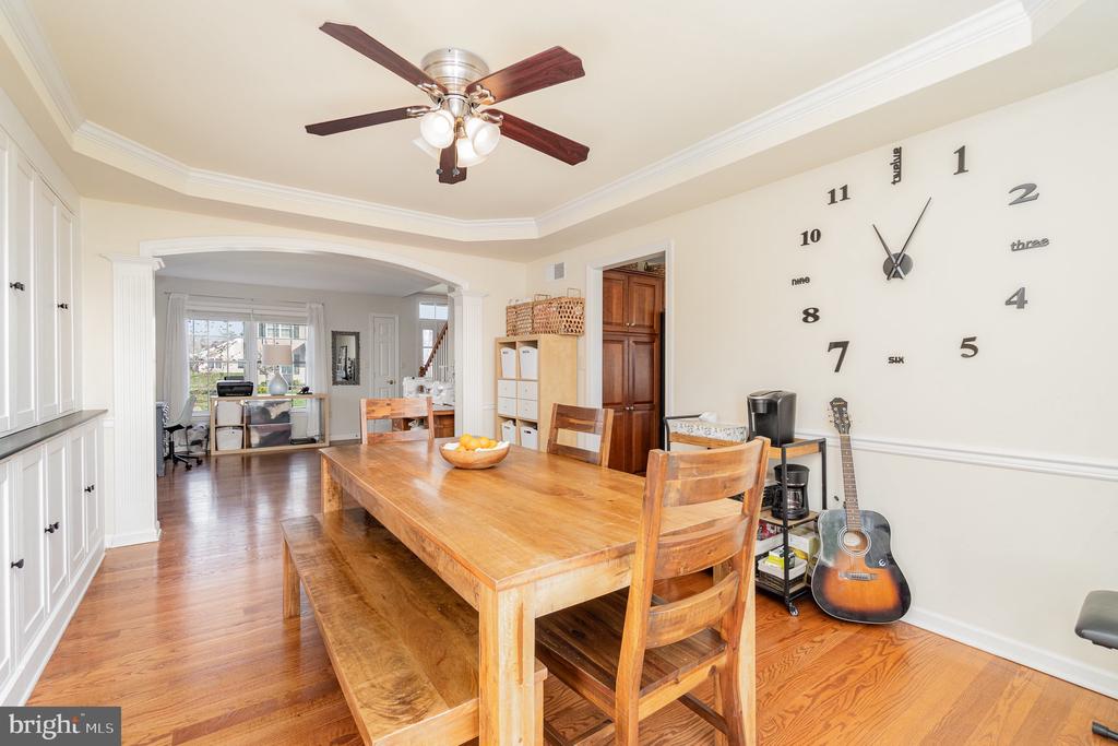Dining room with a long wooden table, hardwood floors, built-in cabinetry, and an oversized wall clock.