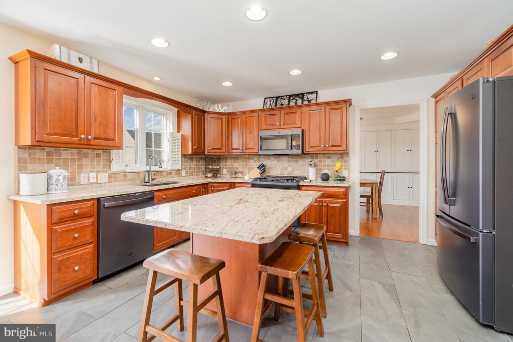 Kitchen with cherry cabinets, granite island seating, stainless steel appliances, and a window above the sink.