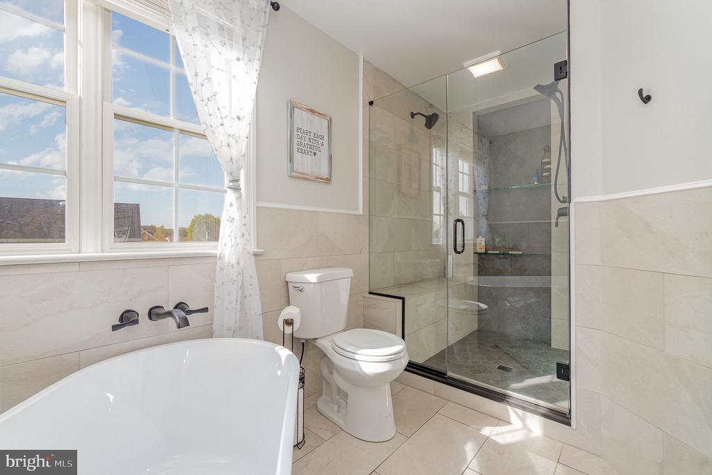 Bathroom with a freestanding tub by a large window and a glass-enclosed shower.