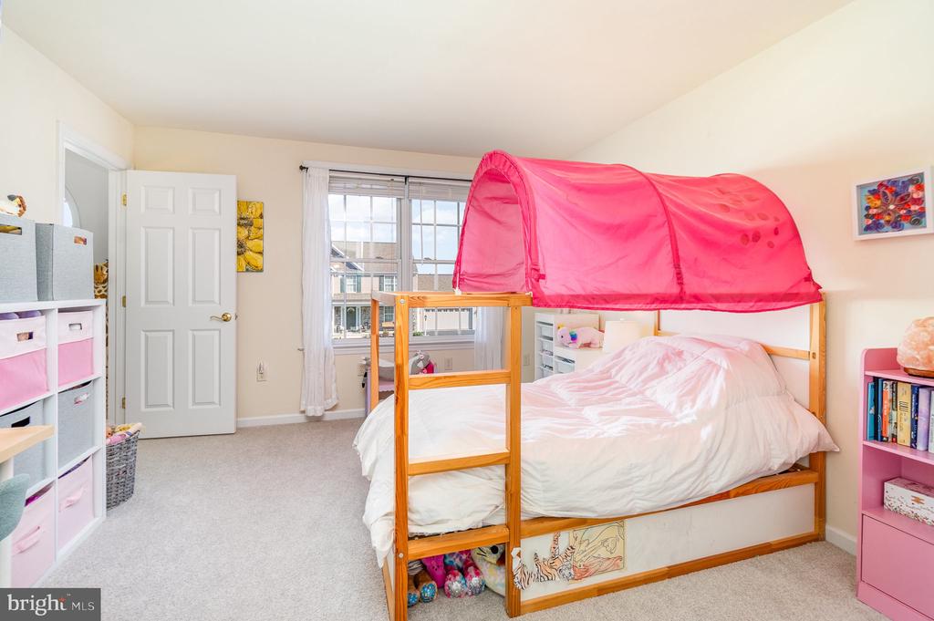 Bedroom with a wooden bed beneath a bright pink canopy and a large window.