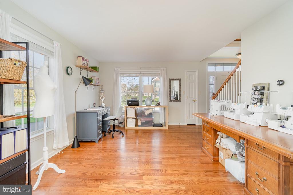 Sewing studio with machines on a long counter, hardwood floors, and large windows.