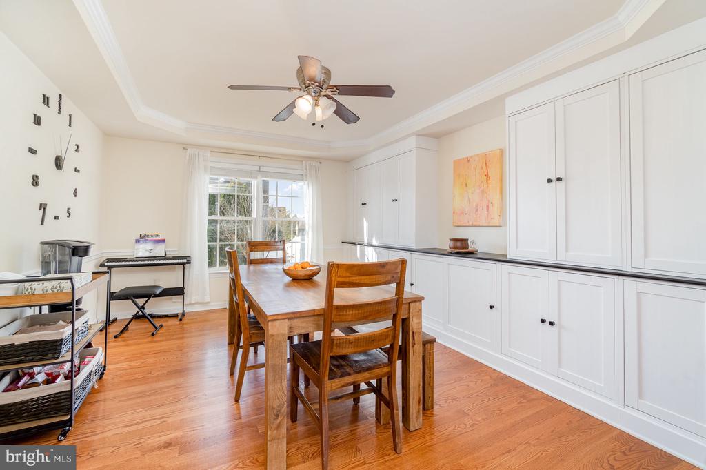 Dining room with white built-in cabinetry, a wooden table, hardwood floors, and a large window.