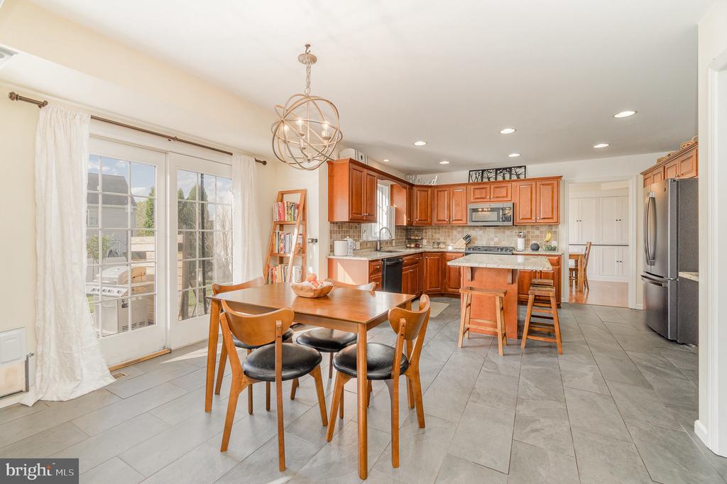 Kitchen and dining area with warm wood cabinets, island seating, and French doors to a patio.