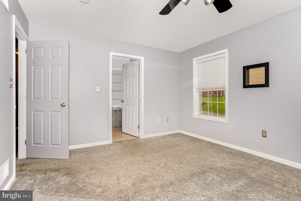 Unfurnished bedroom with beige carpet, a ceiling fan, and a window with white blinds.