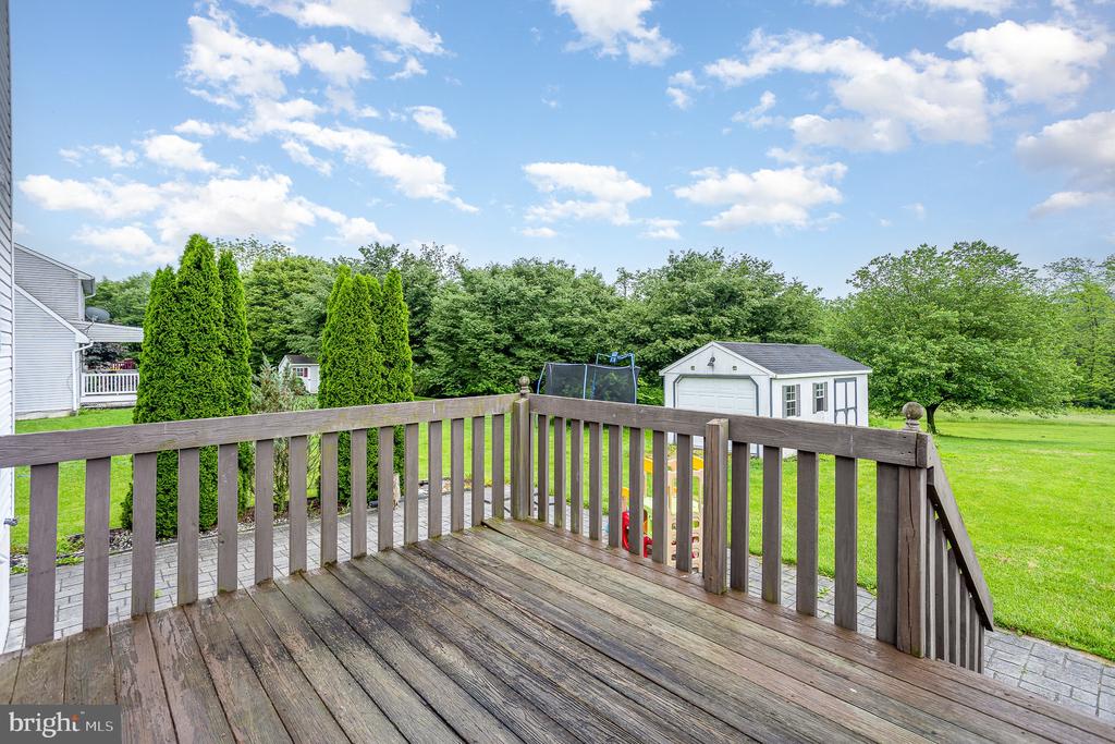 Wooden deck overlooking a green backyard with a trampoline and white storage shed.