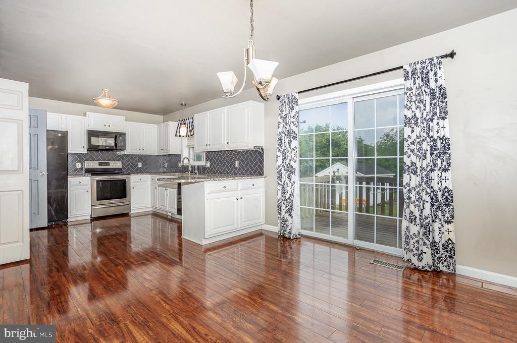 Kitchen with white cabinetry, stainless steel appliances, a central island, and glossy wood floors.