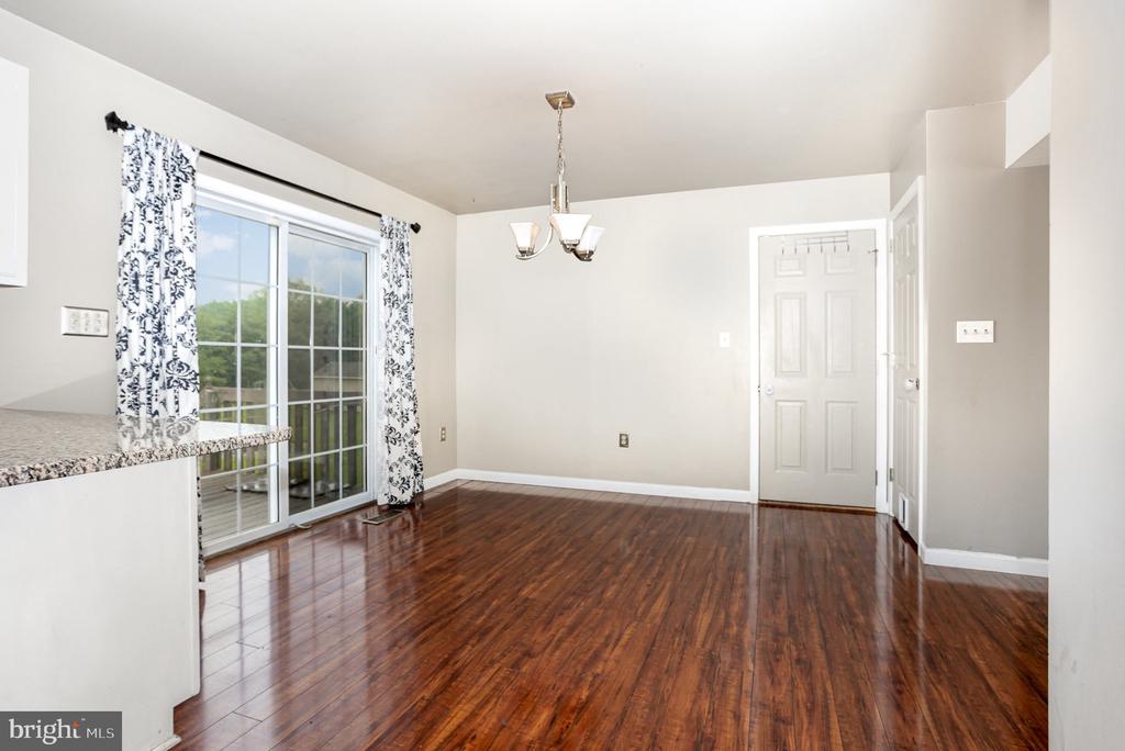 Empty dining room with hardwood floors, a chandelier, and sliding glass doors.