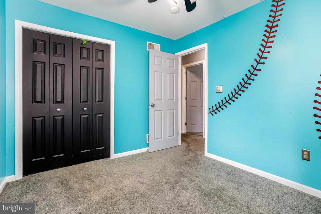 Empty turquoise bedroom with black closet doors and a baseball-stitch wall decoration.