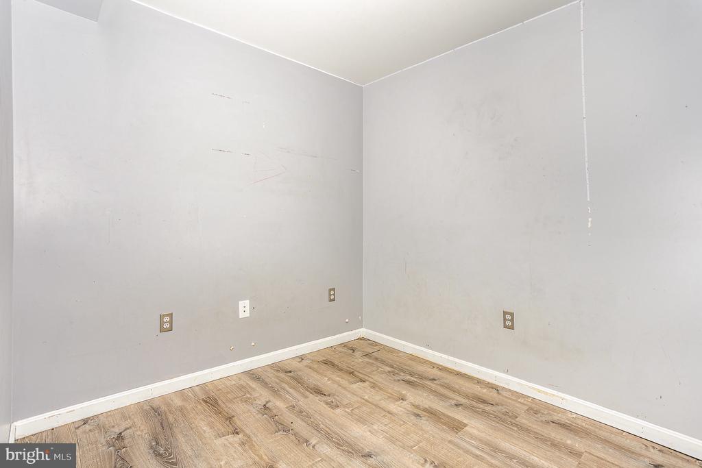 Empty room with gray walls, white baseboards, and wood-look flooring.