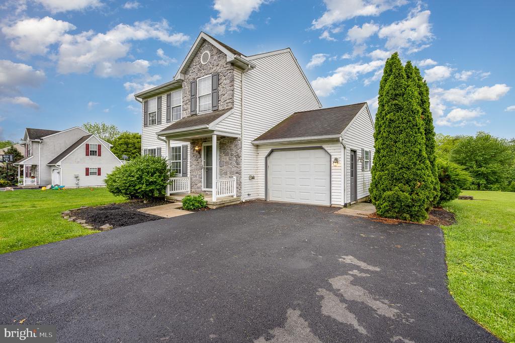 Two-story home with stone accents, covered porch, attached garage, and broad asphalt driveway.