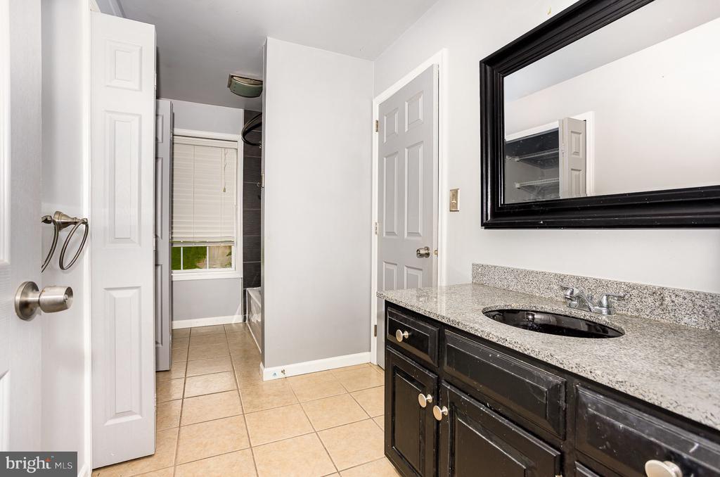 Bathroom vanity with granite countertop, black cabinets, oval sink and large framed mirror.