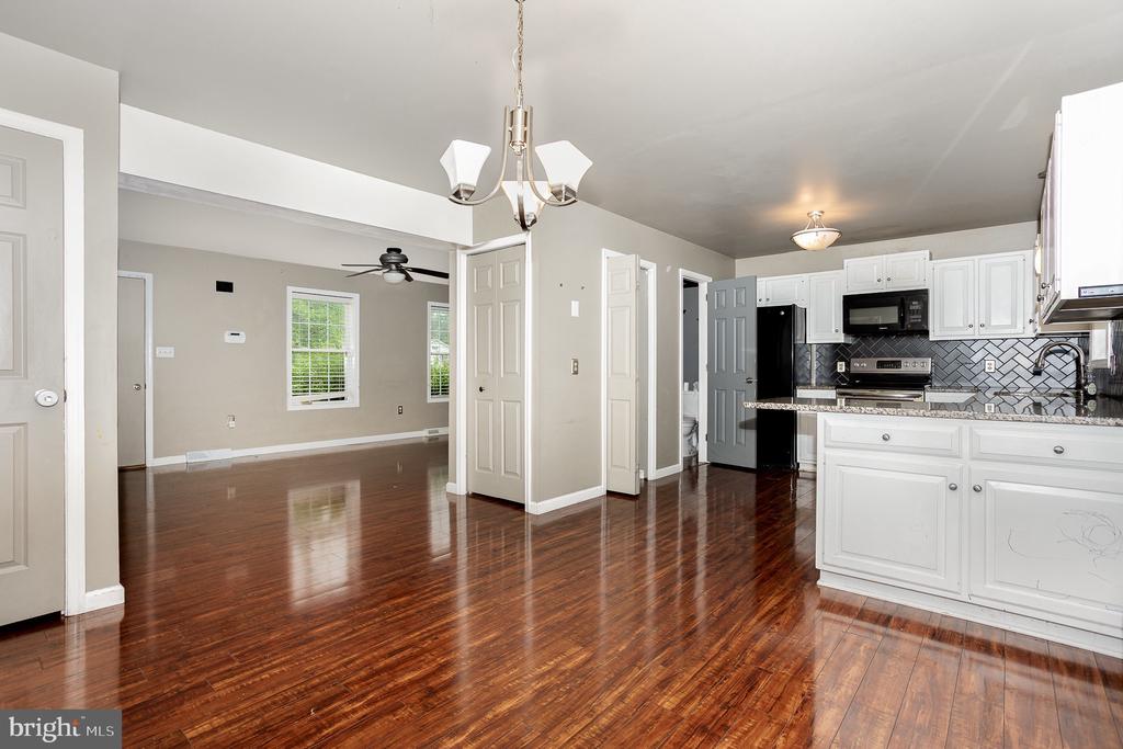 Open kitchen and dining area with white cabinets and glossy hardwood floors.