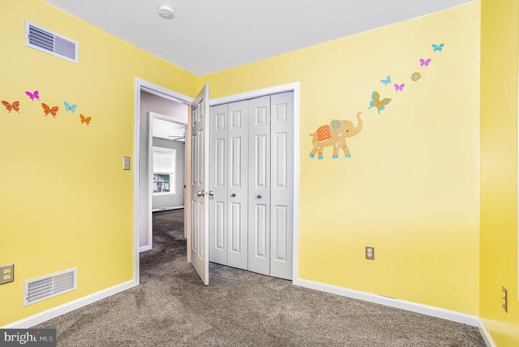 Empty bedroom with yellow walls, butterfly and elephant decals, and white double closet doors.