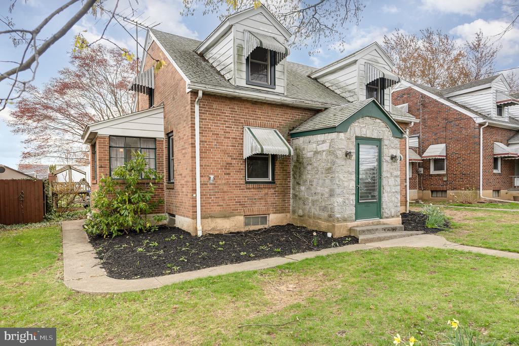 Brick house with white dormers, striped awnings, and a stone entry with a green door.