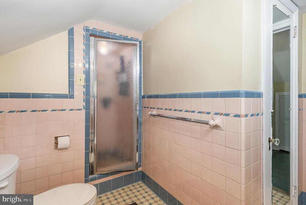 Bathroom with pink tile, blue trim, a frosted-glass shower door, and tiled floor.