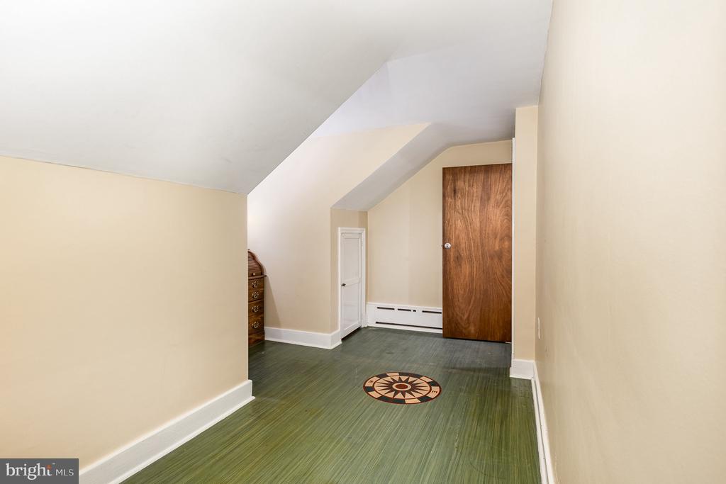 Upstairs room with a sloped ceiling, green flooring, and a compass-pattern medallion.