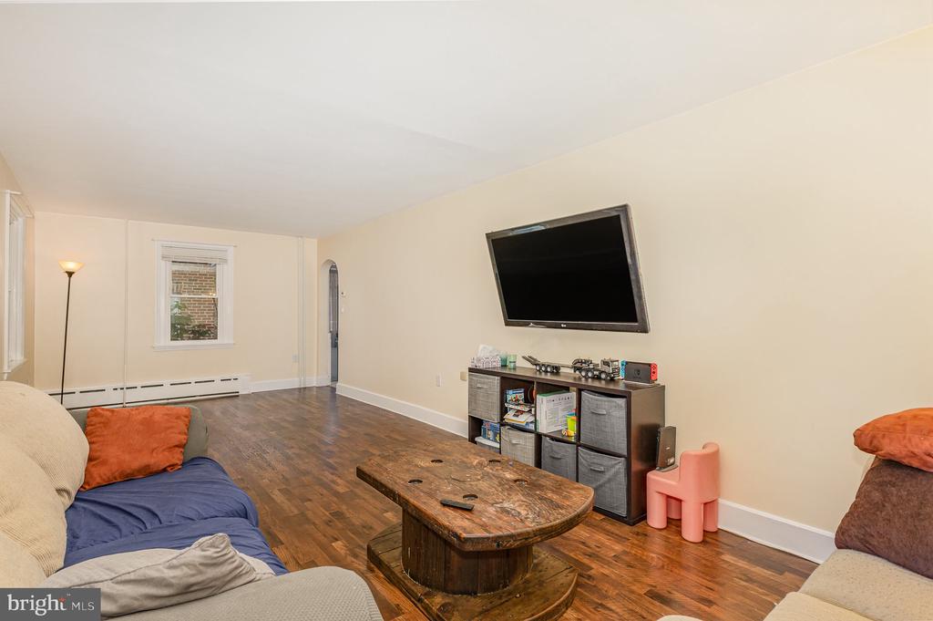 Furnished living room with dark wood floors, rustic coffee table, and wall-mounted television.