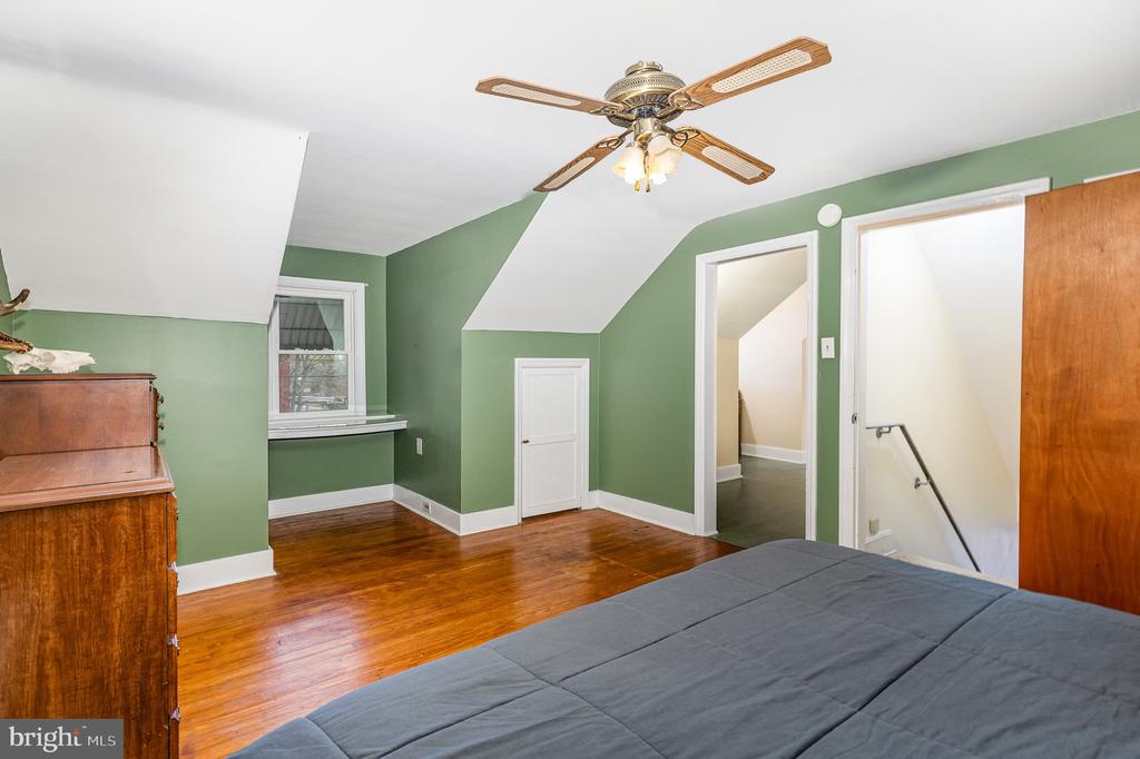 Bedroom with green walls, hardwood floors, and a dormer window.
