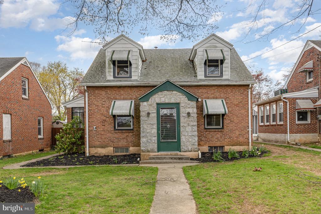 Brick two-story home with a stone entry, green door, and paired roof dormers.