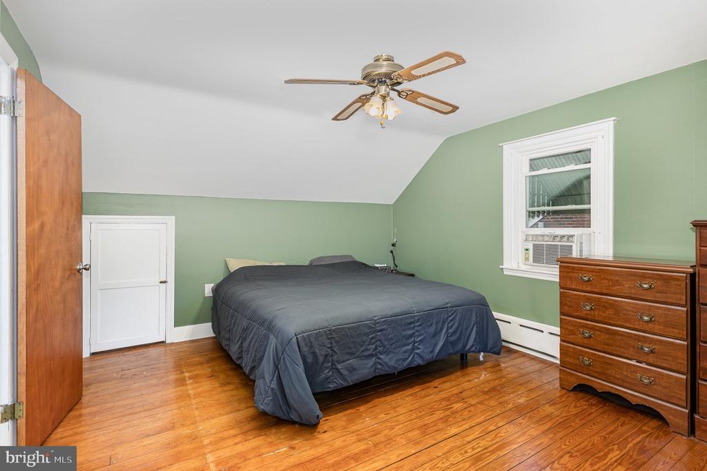 Bedroom with sage green walls, hardwood floors, a gray bed, and a window air conditioner.