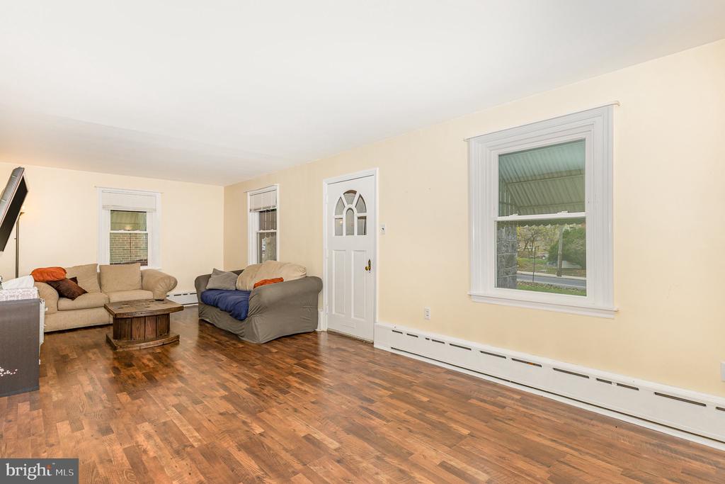 Furnished living room with wood-look flooring, two sofas, a coffee table, and white-trimmed windows.