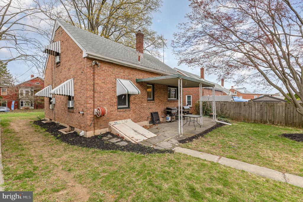 Red brick house with a covered patio and grassy yard.