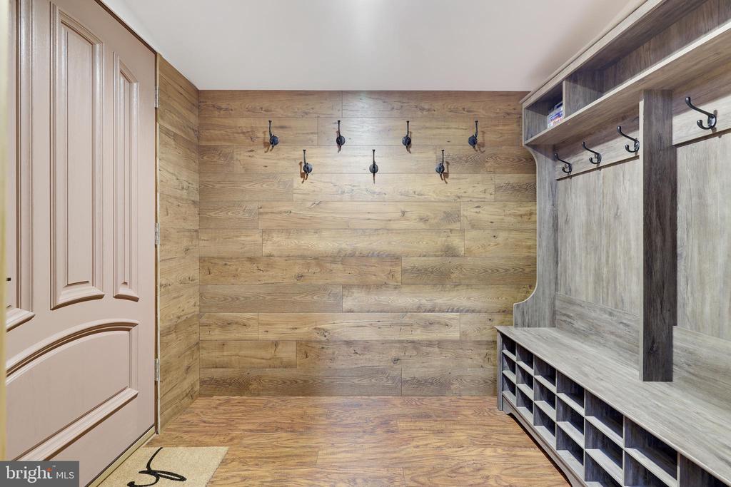 Mudroom with wood-plank walls, wall hooks, and a built-in bench with storage cubbies.