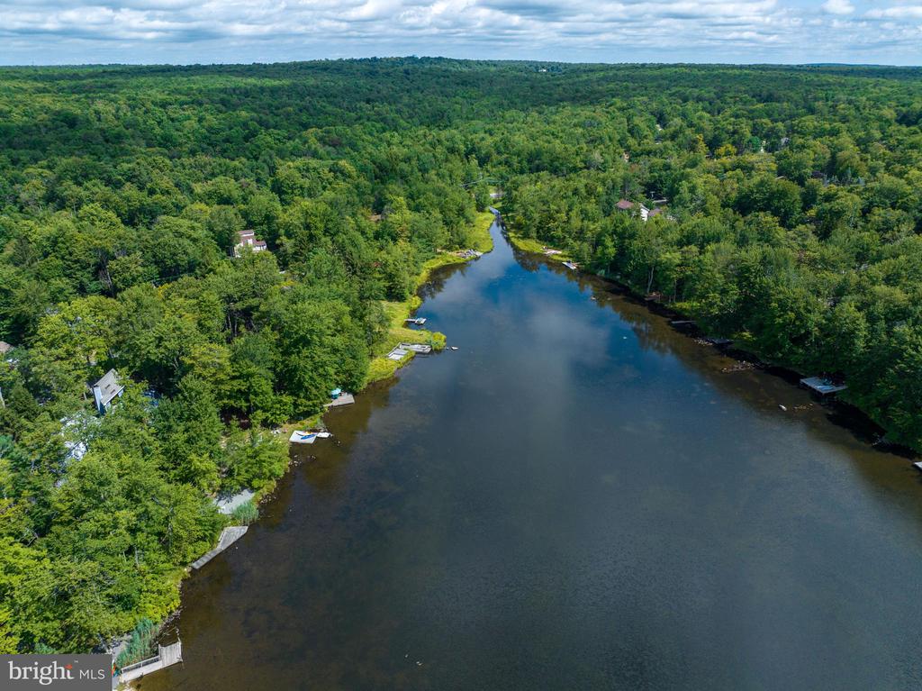 Aerial view of a wooded lake with homes, docks, and boats along the shoreline.