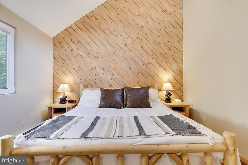 Bedroom with a log-style bed, white bedding, and a diagonal pine accent wall.