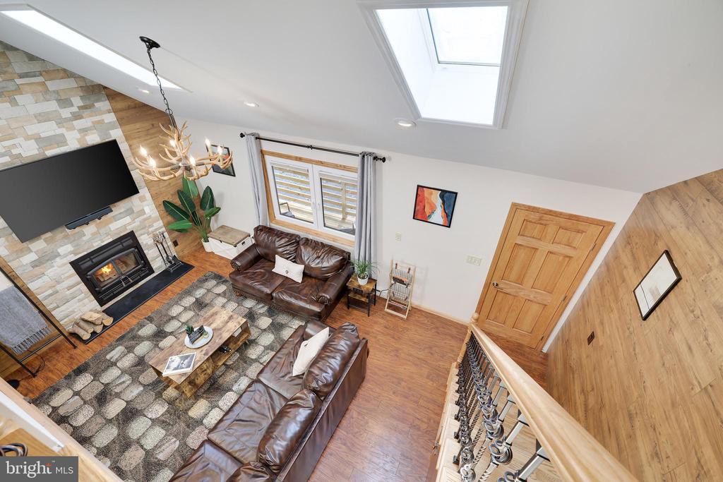 Living room with leather sofas, stone fireplace wall, and skylight, viewed from above.