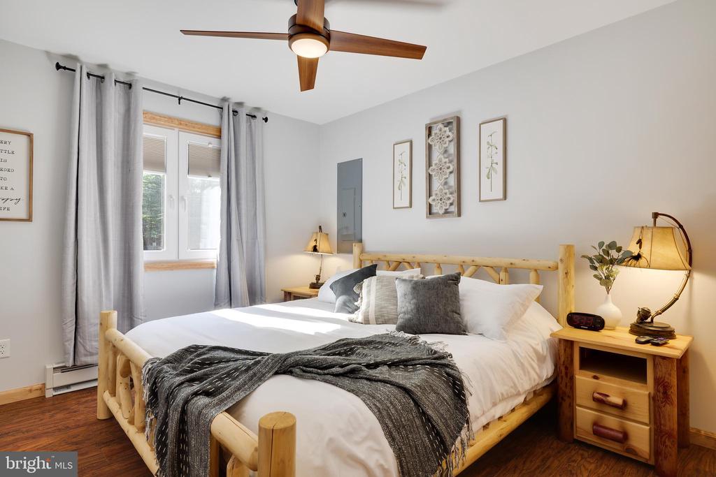 Bedroom with a log-style wooden bed, white bedding, gray throw, and curtained windows.