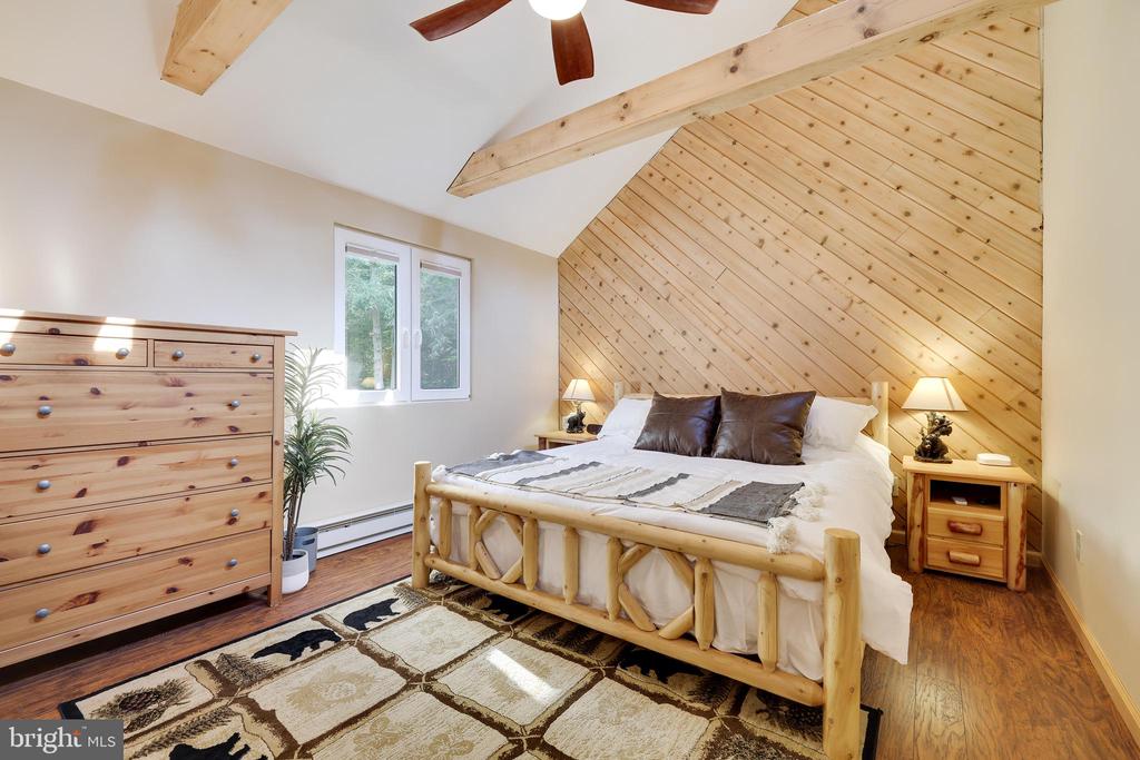 Bedroom with a log-style bed beneath a vaulted, wood-plank accent wall.