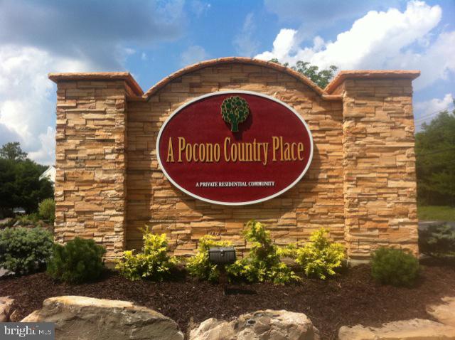 Entrance monument for A Pocono Country Place, with a red community sign set into a stone wall.