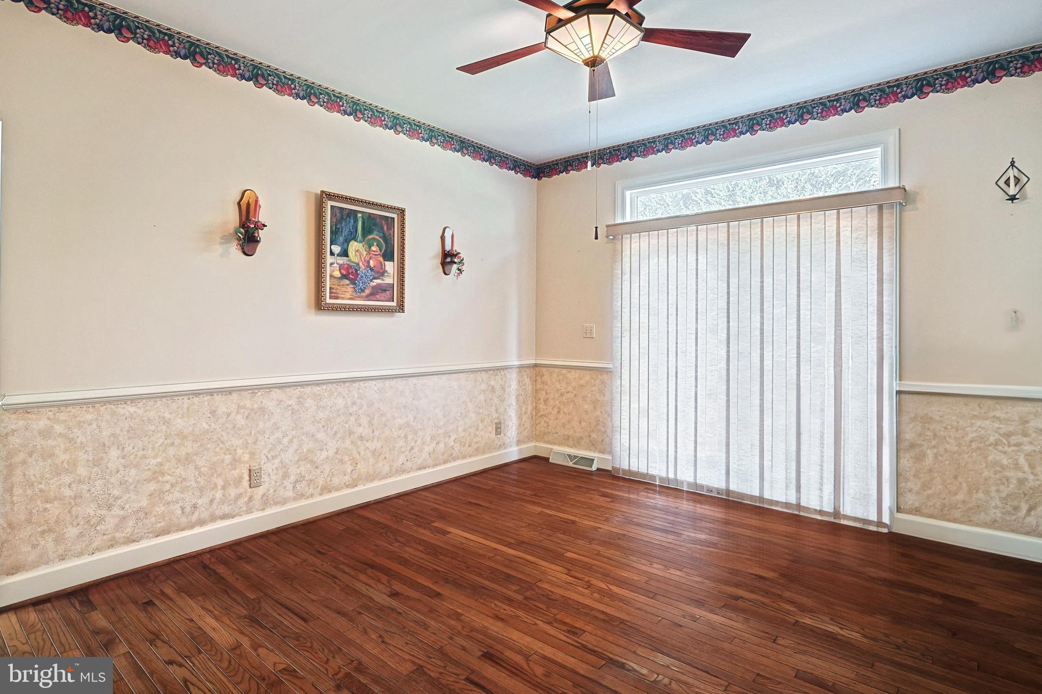 Dining room with hardwood floors, sliding glass doors, vertical blinds, and a ceiling fan with light.