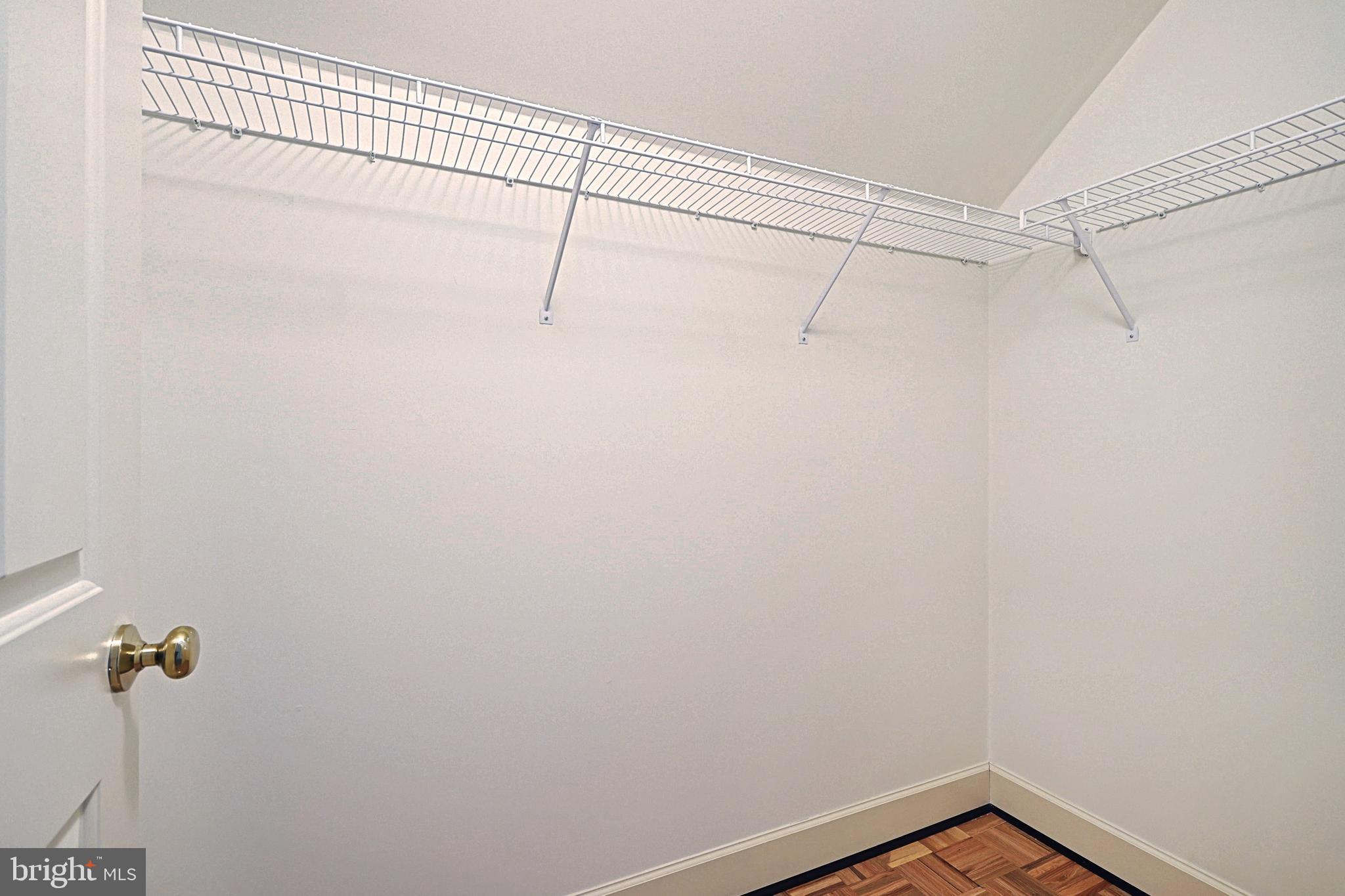 Empty walk-in closet with wire shelving and a parquet wood floor.