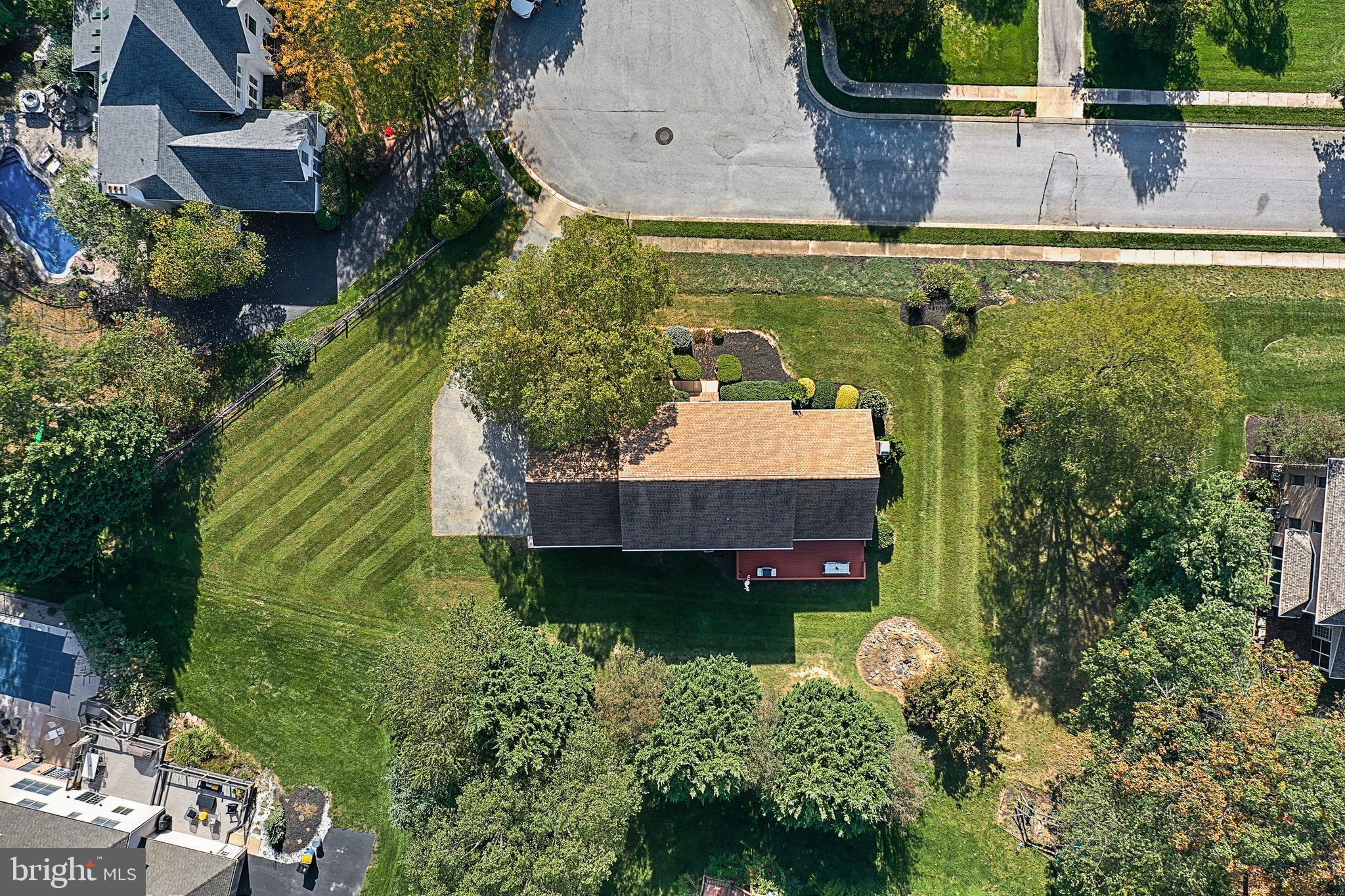 Aerial view of a home with a broad lawn, landscaped garden, and driveway.
