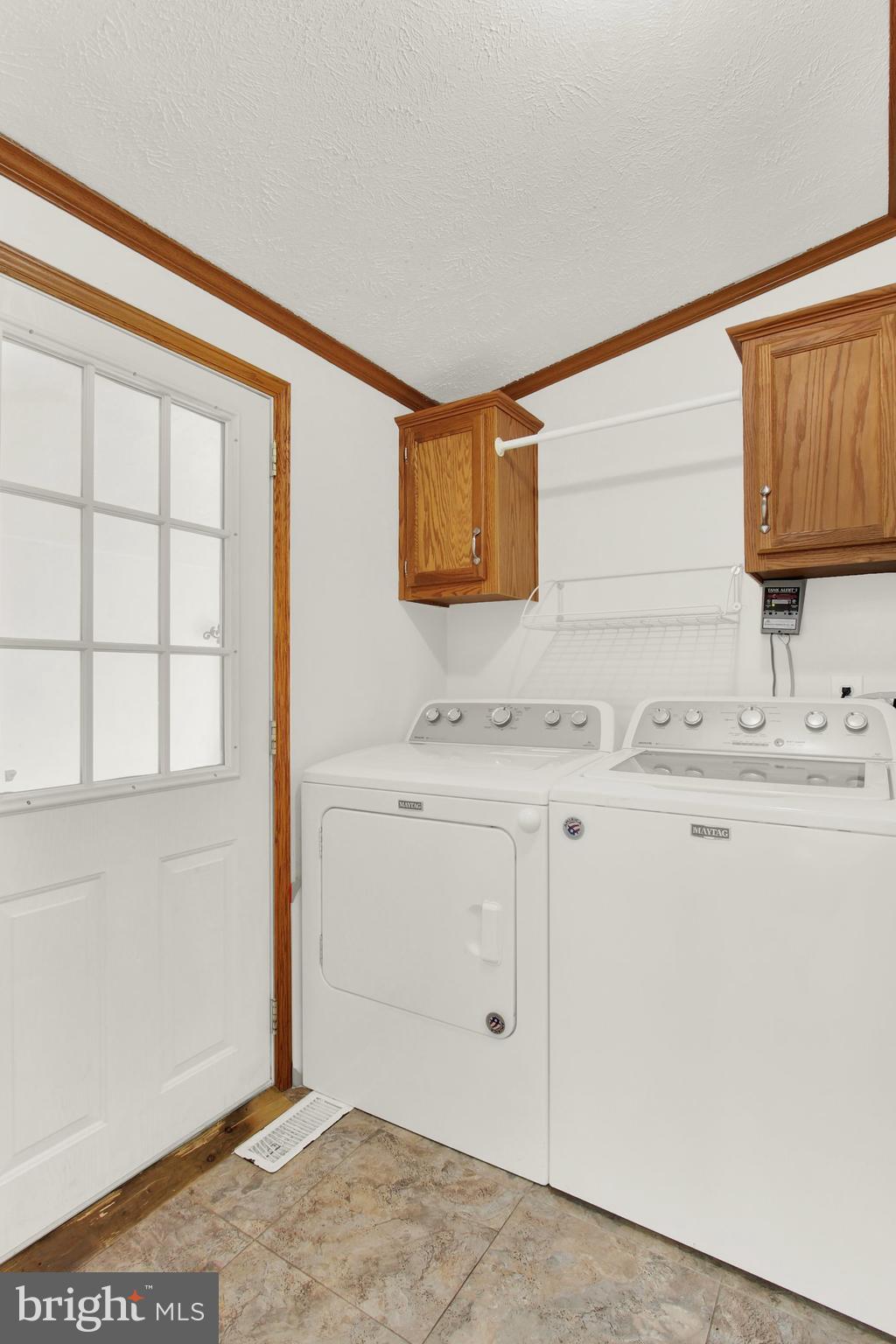 Laundry room with white washer and dryer, oak cabinets, and a glass-paneled door.